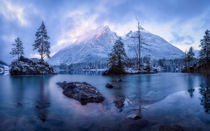 Winter mountain lake with snow-covered trees and rocks