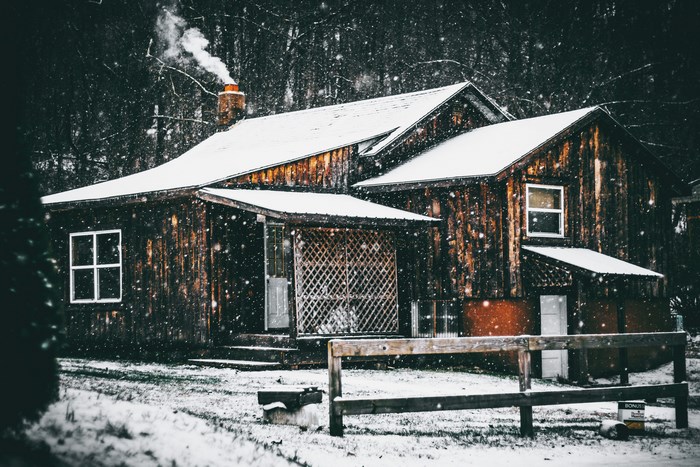 Wooden cabin in the snow with smoke from chimney