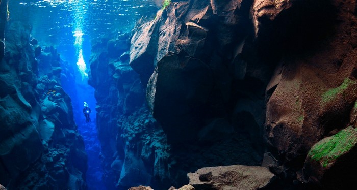 Scuba diver in a deep underwater fissure in Iceland