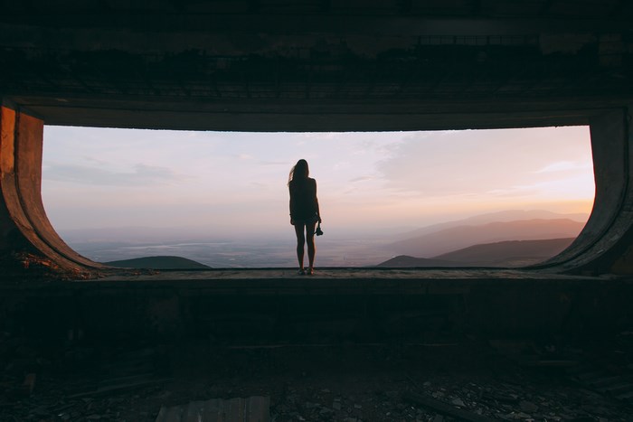 Woman with camera overlooking mountains at sunset