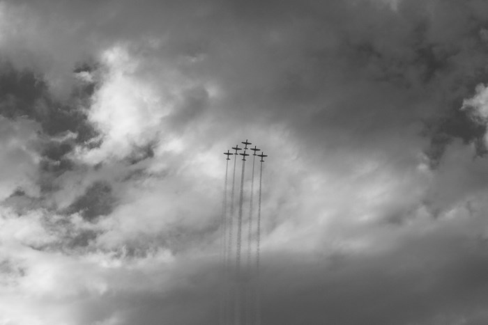 Seven airplanes flying in formation against a cloudy sky