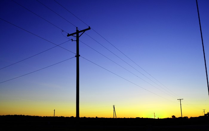 Silhouette of utility poles against a dusk sky