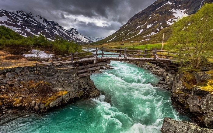 Mountain river with a wooden bridge in Norway