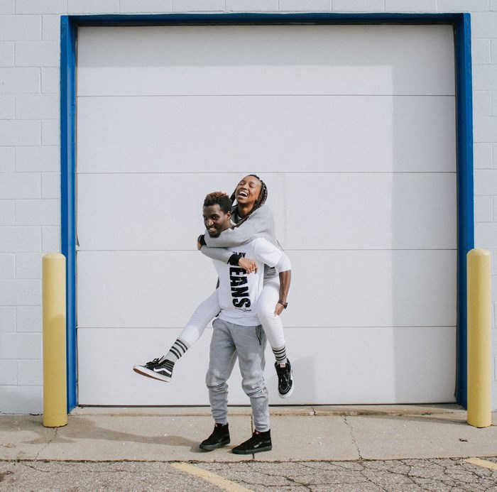 Couple having fun piggyback ride in front of garage door