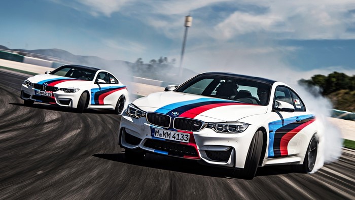 Two BMW M4 cars drifting on a race track
