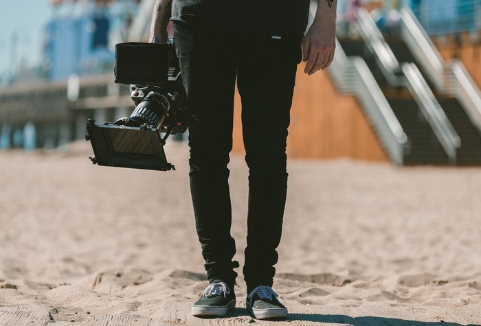 Man holding a video camera on a sandy beach