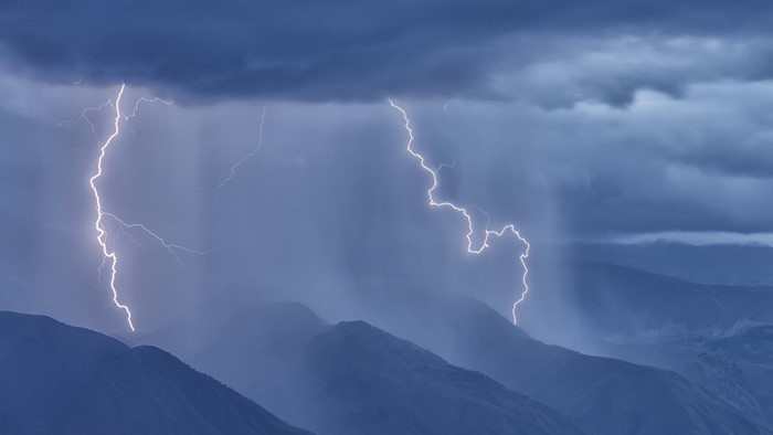 Lightning strikes over mountains during a rain storm