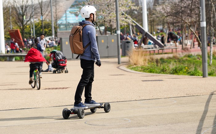 Young man on an electric skateboard in a park