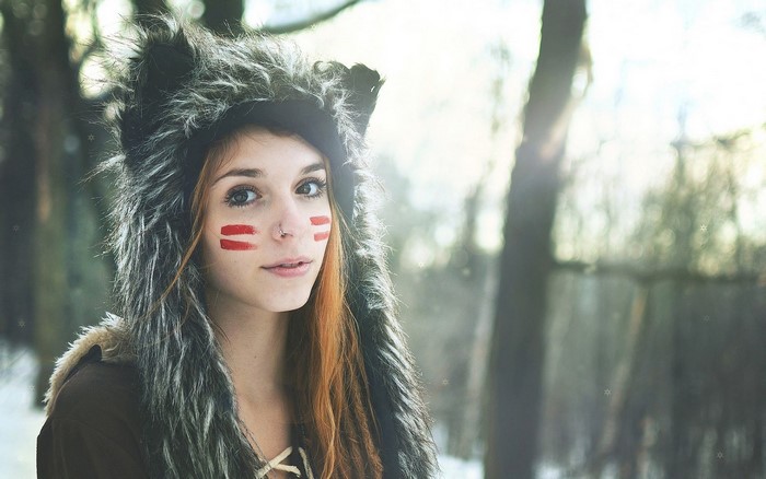Woman with wolf hat and face paint in forest
