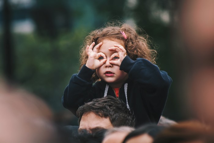 Girl looking through hands on shoulders