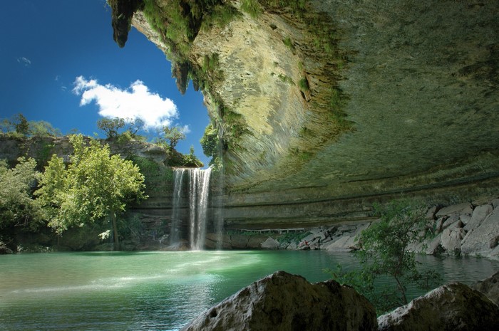 Waterfall cascading into a natural pool under a rock overhang
