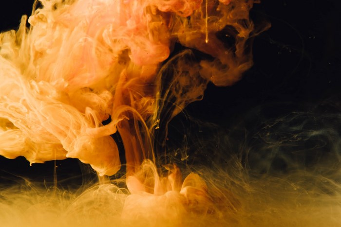 Orange and yellow smoke swirling in black liquid