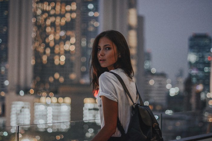 Woman with backpack in city at night