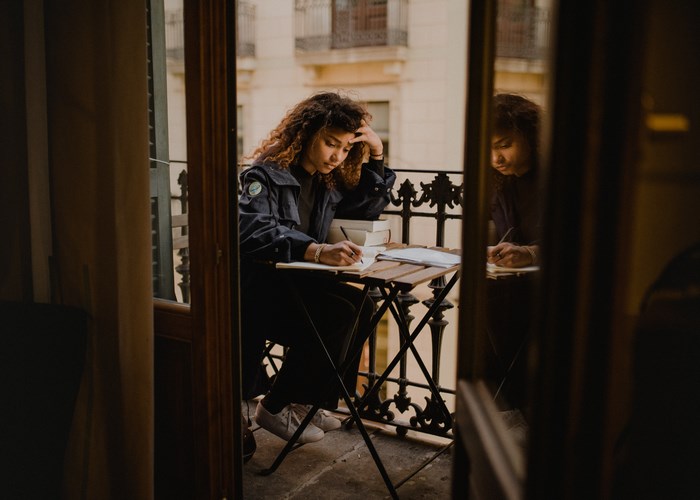 Woman writing on a balcony with books