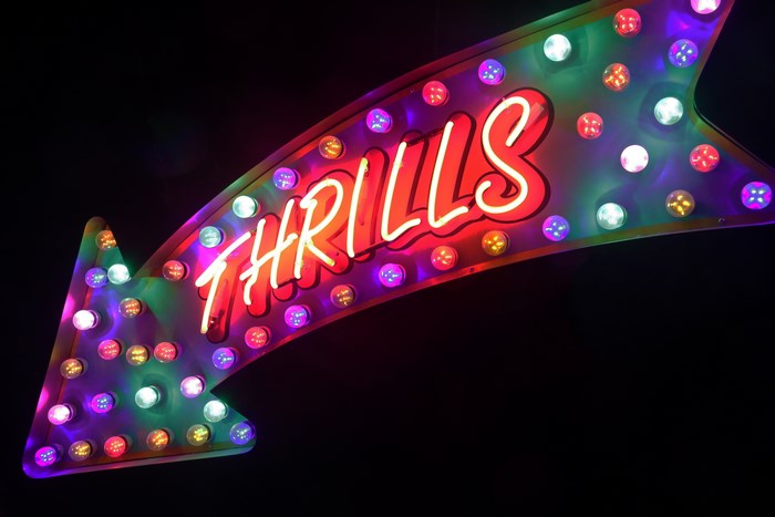 Neon arrow sign with the word THRILLS