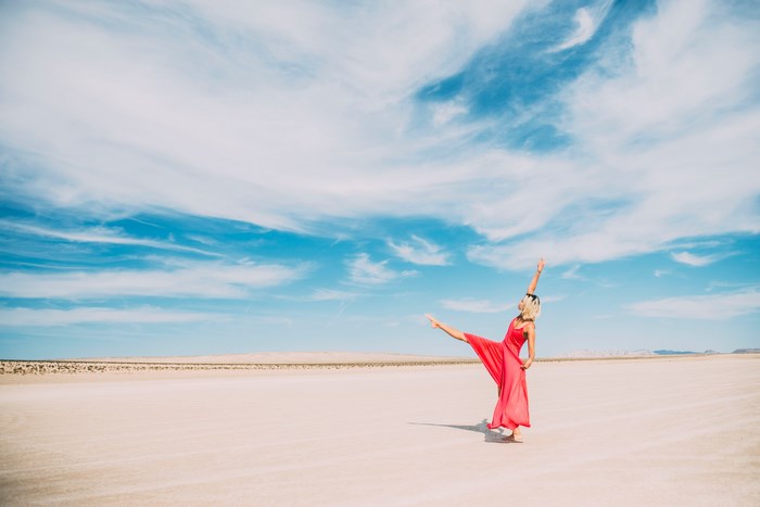 Woman in red dress dancing in a desert