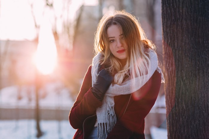 Young woman in winter coat and scarf at sunset