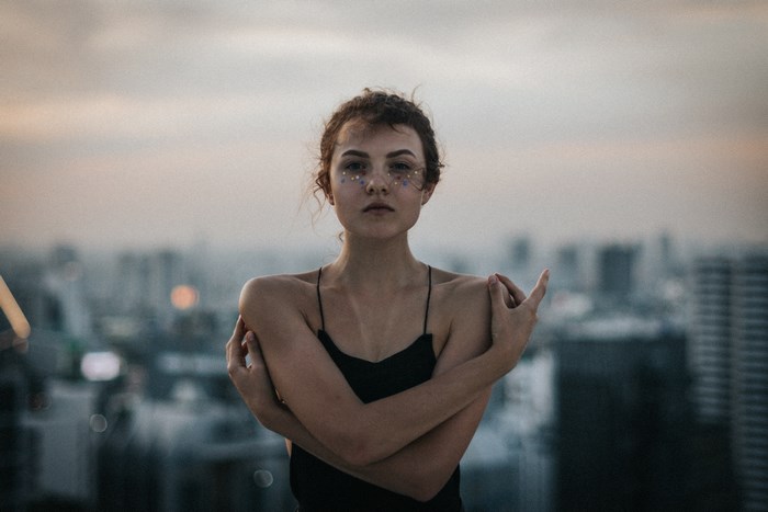 Woman with glitter makeup on a city rooftop at dusk
