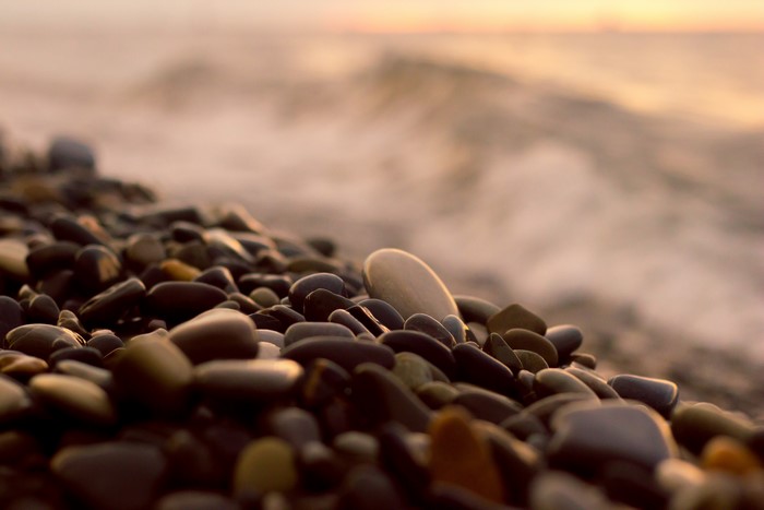 Pebbles on a beach with waves at sunset