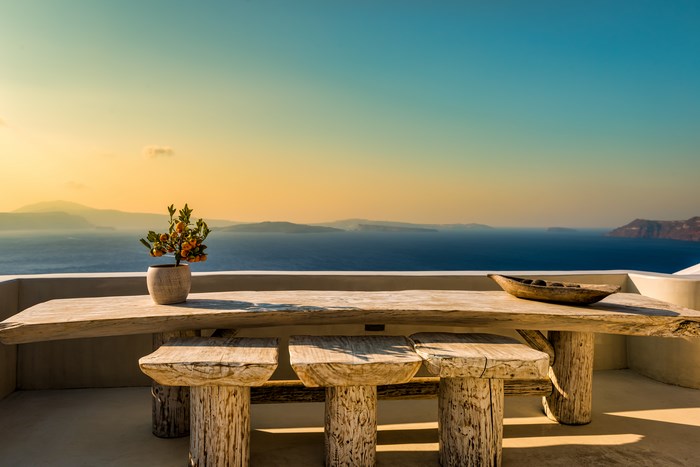 Wooden table and stools on a rooftop overlooking the sea at sunrise