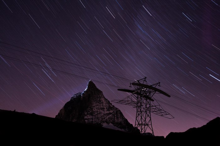 Matterhorn mountain under star trails with power lines