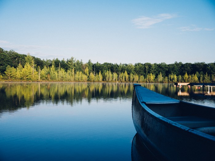 Canoe on a calm lake with forest reflection