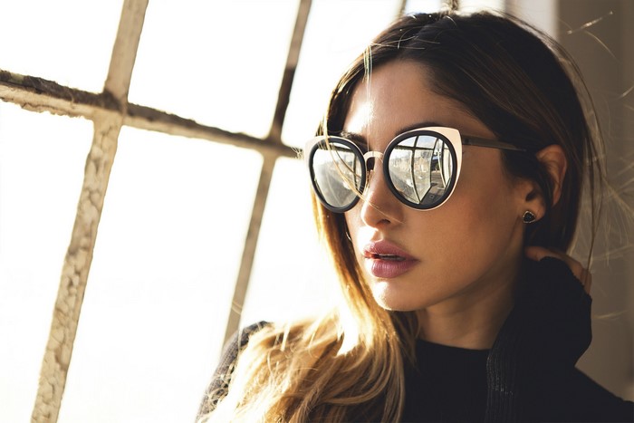 Woman wearing sunglasses by a window