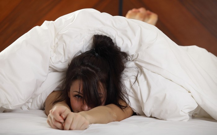 Woman lying in bed under white duvet