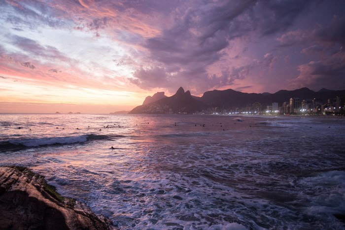 Sunset over Ipanema Beach with surfers and mountains