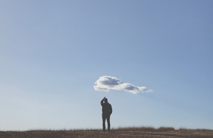 Man pointing at a cloud in a blue sky