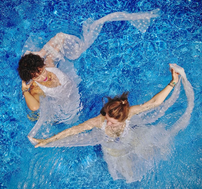 Two women in white dresses dancing in a pool