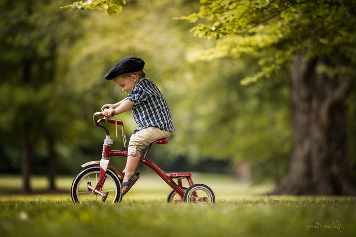 Boy on a red tricycle in a park