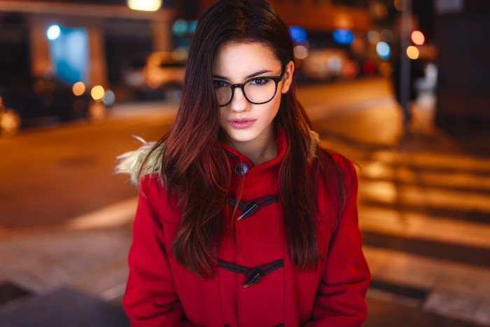 Woman with glasses wearing a red coat at night