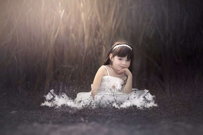 Young girl in white dress sitting in tall grass