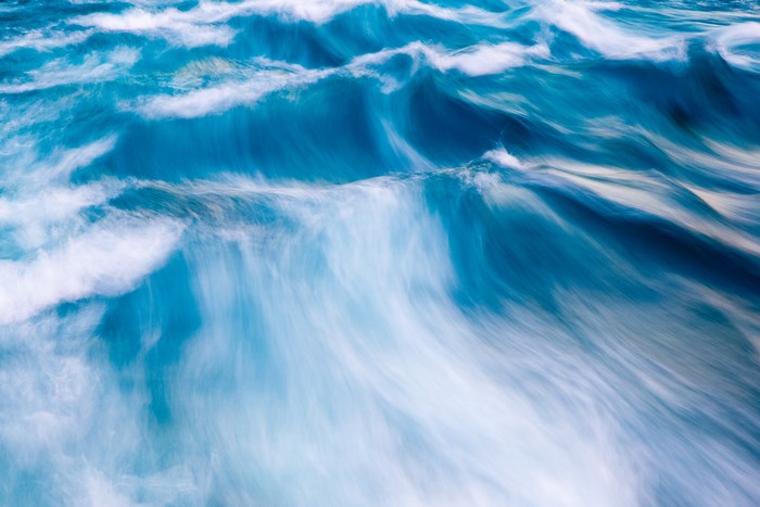 Long exposure of blue ocean waves with white foam