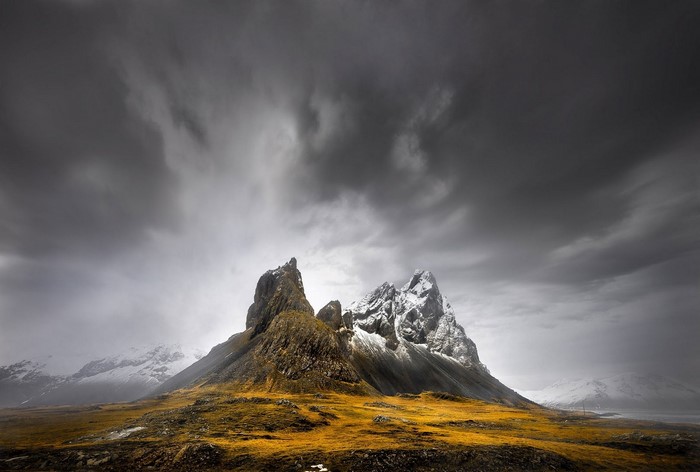 Snowy mountain peak under dark clouds in Iceland