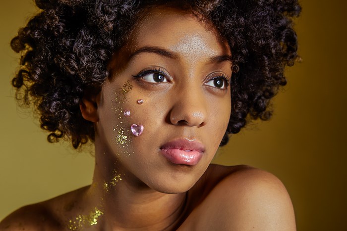 Black woman with curly hair and glitter makeup