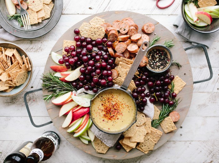 Cheese fondue with grapes, apples, crackers, and sausage