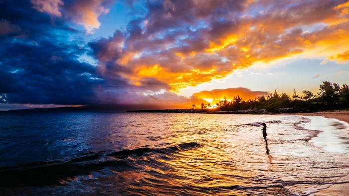 Sunset over the ocean with a person on the beach