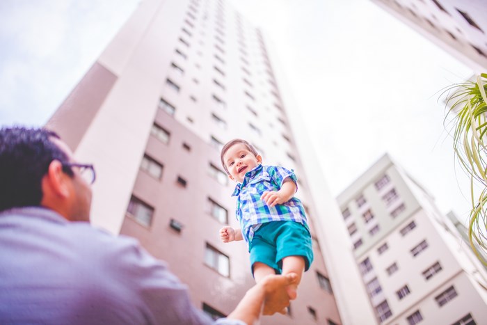 Father holding baby up in front of skyscrapers