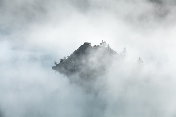 Floating island with ruins and trees in fog