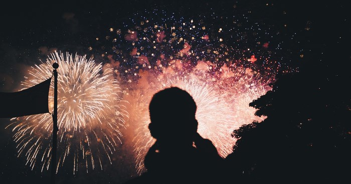 Silhouette of a person watching fireworks with a flag