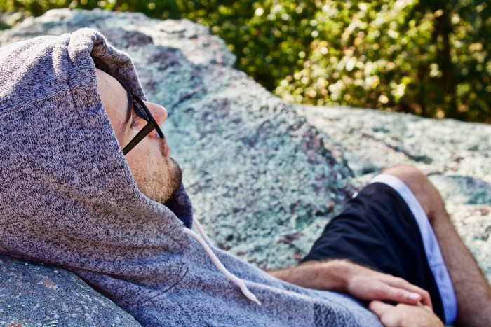 Man in hoodie relaxing on a rock