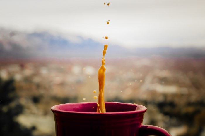 Coffee splashing into a red mug with a blurred background