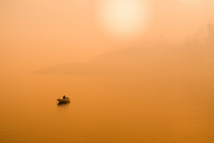 Fisherman in a boat on the water at sunset