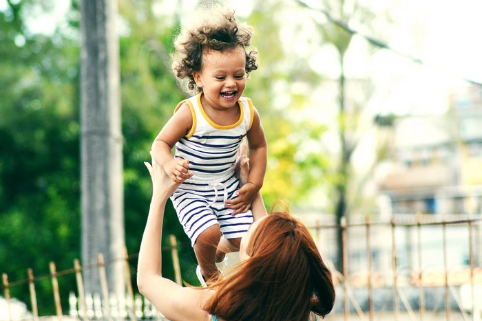 Mother throwing laughing baby in the air