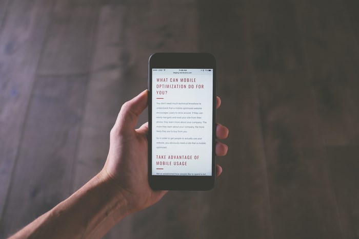 Hand holding iPhone displaying mobile optimization website