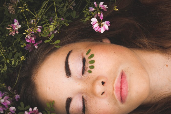 Woman with flowers and leaves on face