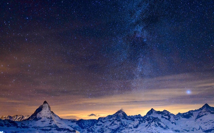 Snowy mountains under a starry night sky