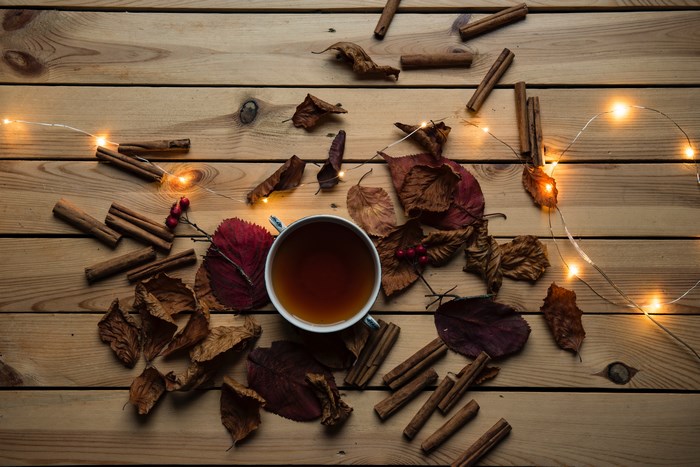 Autumn flatlay with tea, cinnamon, and fairy lights on wood